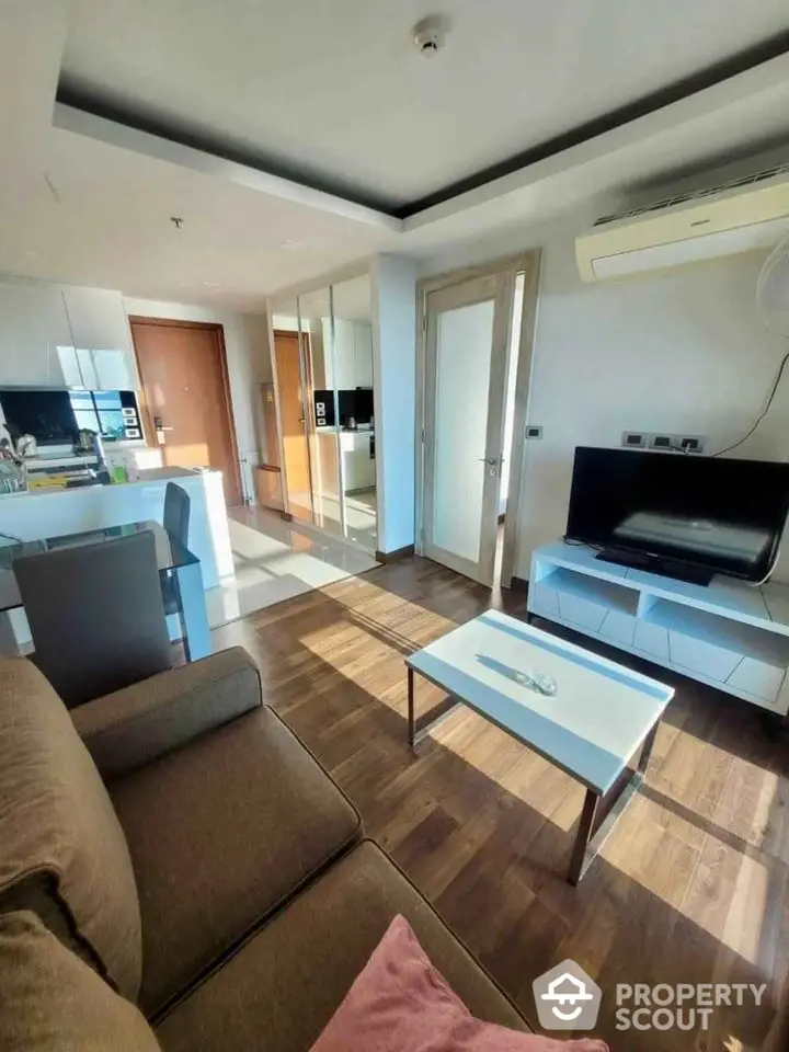 Modern living room with sleek furniture and natural light, featuring a cozy sofa and entertainment center.