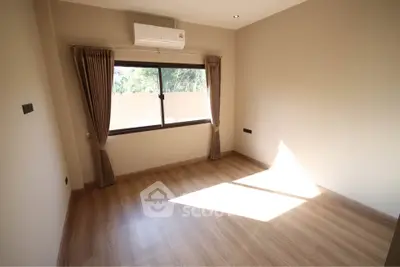 Spacious empty room with wooden flooring and large window, perfect for customization.
