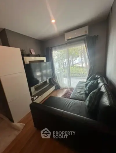 Cozy living room with large window and modern furnishings in a stylish apartment.