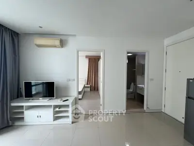 Modern apartment interior with open living area and view into bedroom and bathroom.