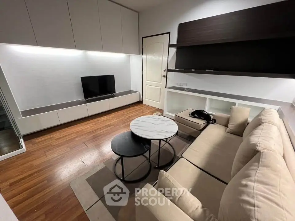 Modern living room with sleek furniture and wooden flooring, featuring a cozy sofa and stylish coffee table.