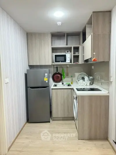 Modern compact kitchen with sleek appliances and stylish cabinetry in a cozy apartment.
