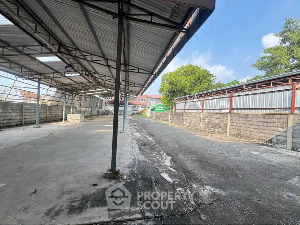 Spacious industrial outdoor area with metal roofing and concrete flooring, ideal for storage or workshop use.