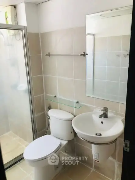 Modern bathroom with shower, toilet, and sink in a sleek, tiled design.