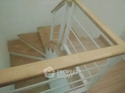 Modern wooden staircase with sleek railing in a contemporary home interior.