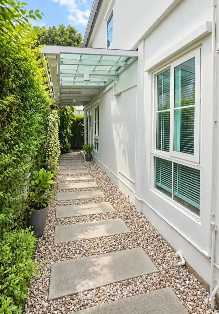 Charming garden pathway with modern glass canopy and lush greenery