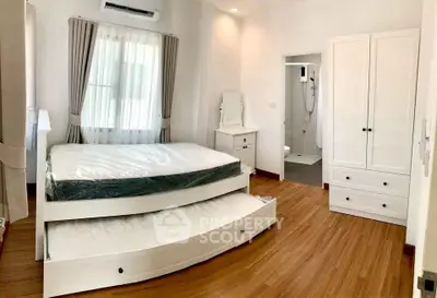 Spacious bedroom with wooden flooring and ensuite bathroom in modern home.
