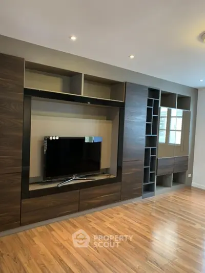 Modern living room with sleek wooden entertainment center and hardwood floors