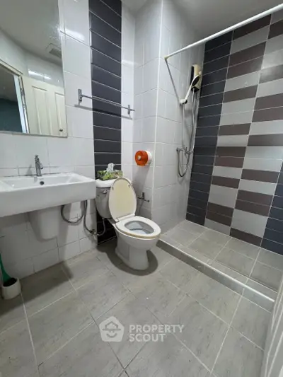 Modern bathroom with sleek tiles and walk-in shower in a contemporary apartment.