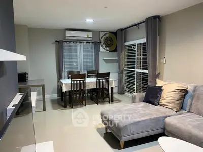 Modern living room with cozy sectional sofa and dining area, featuring elegant decor and ample natural light.