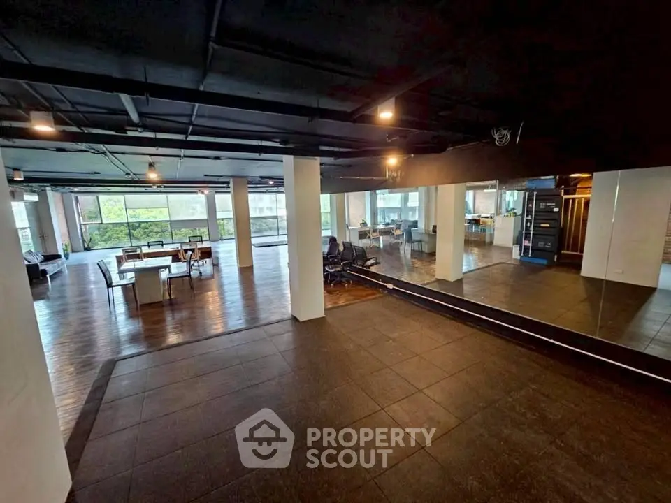 Spacious open-plan office with modern design and large windows offering natural light.