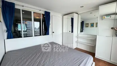 Spacious bedroom with city view and modern white furniture.