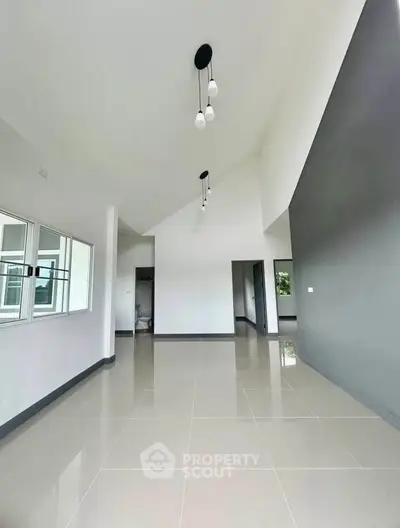 Spacious modern living room with high ceilings and elegant lighting fixtures.
