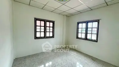 Spacious empty room with tiled floor and two large windows, perfect for customization.
