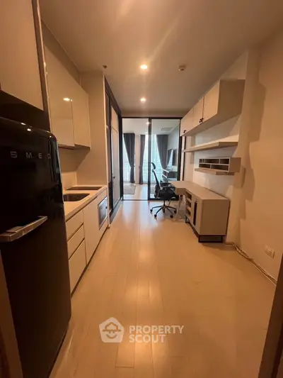 Modern kitchen with sleek appliances and open layout leading to a stylish living area.