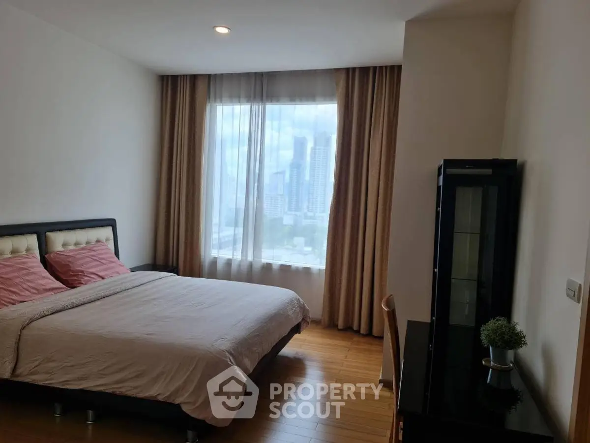 Spacious bedroom with city view, wooden flooring, and elegant decor.