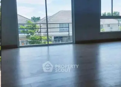 Spacious room with large windows offering a serene neighborhood view.