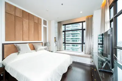Luxurious modern bedroom with large windows and city view, featuring elegant decor and sleek furnishings.