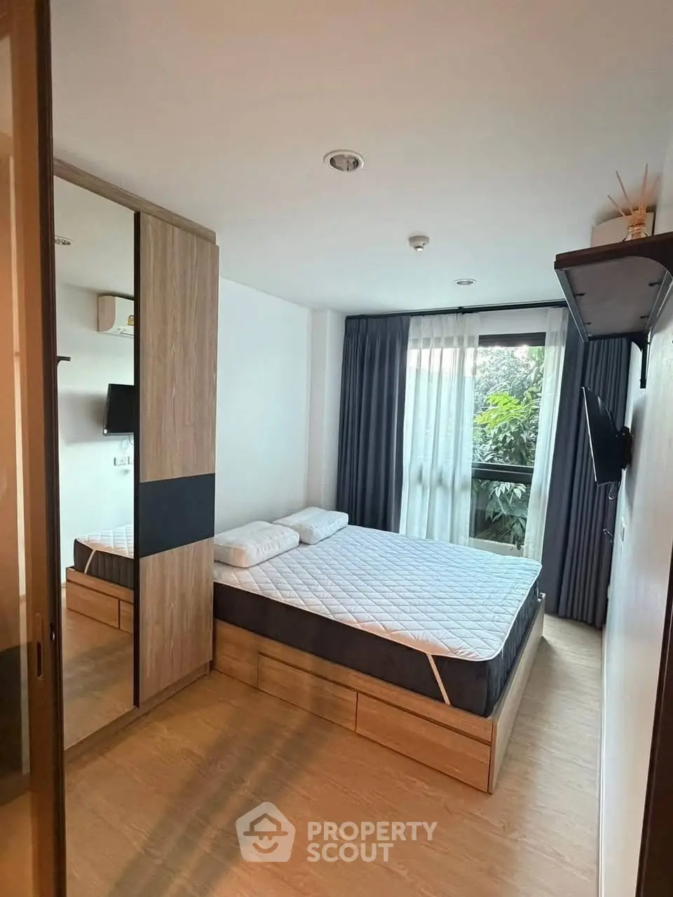 Modern bedroom with large window and stylish wooden furniture