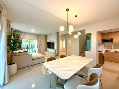 Spacious modern living and dining area with elegant lighting and open kitchen layout.