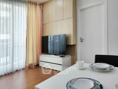 Modern living room with sleek TV setup and dining area in bright apartment