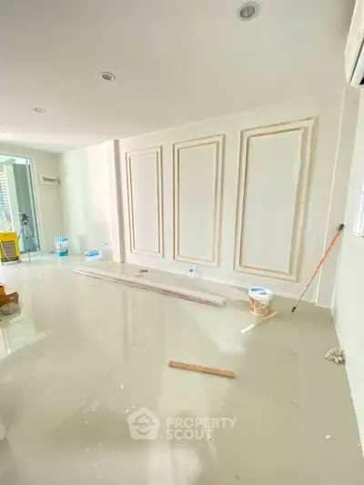 Spacious interior under renovation with elegant wall paneling and glossy tiled flooring.