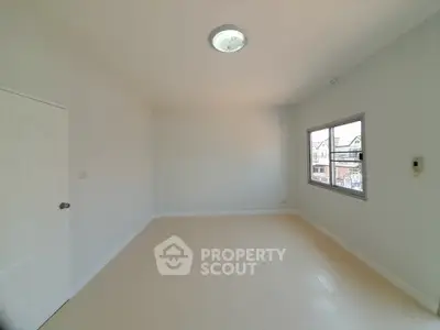 Spacious empty room with large window and neutral tones, perfect for customization.