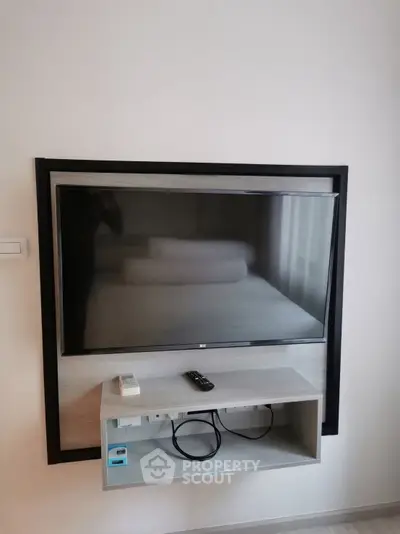 Modern bedroom with wall-mounted TV and sleek shelf, perfect for contemporary living.