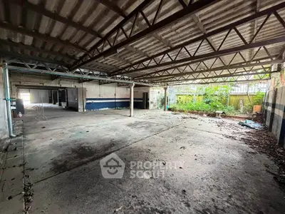Spacious industrial-style garage with high ceilings and open layout, perfect for storage or workshop use.