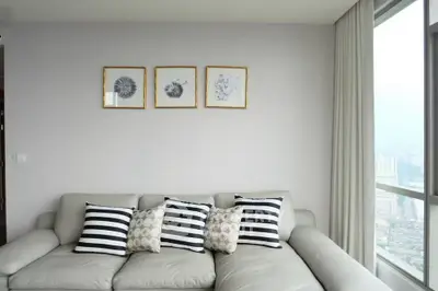 Modern living room with stylish sofa and city view window, featuring elegant wall art.