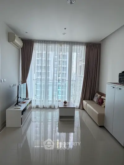 Modern living room with large windows and city view, featuring sleek furniture and natural light.