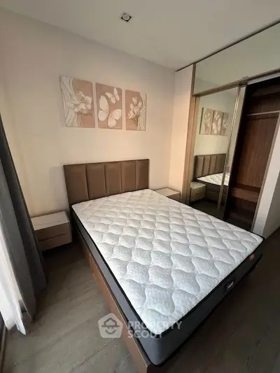 Modern bedroom with stylish decor and mirrored wardrobe in a cozy apartment.