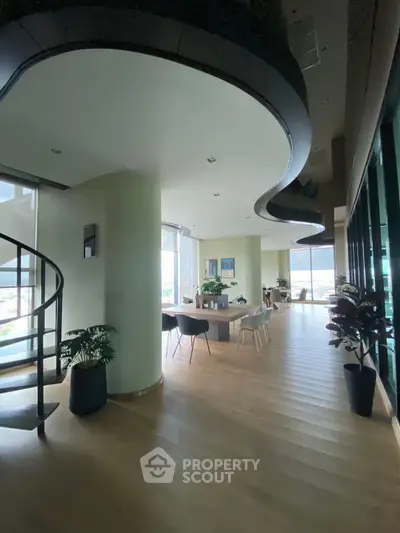 Spacious modern living area with elegant spiral staircase and panoramic windows.