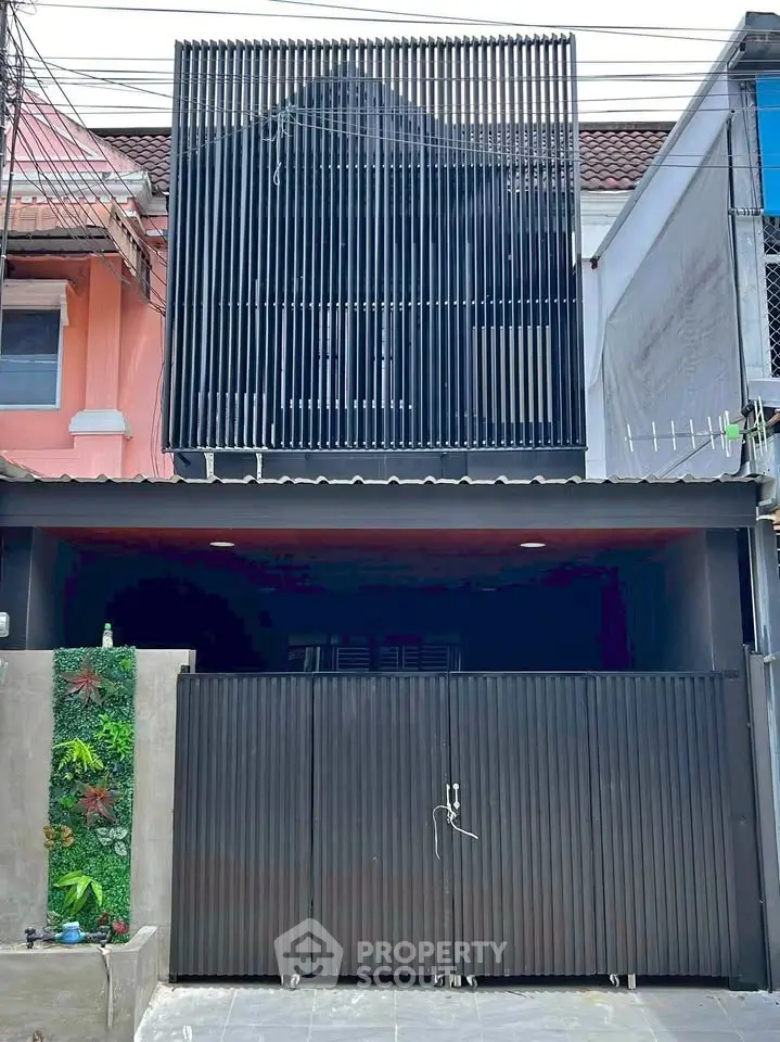 Modern urban townhouse with sleek black facade and gated entrance, showcasing contemporary architectural design.