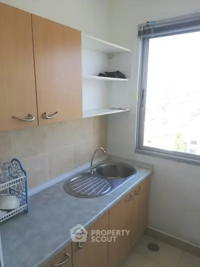Compact kitchen with window view and wooden cabinets