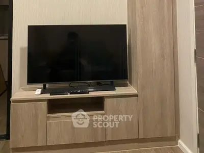 Modern living room with sleek wooden TV cabinet and flat-screen television.