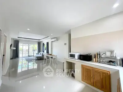 Spacious open-plan living room with modern kitchen and large windows leading to a balcony.