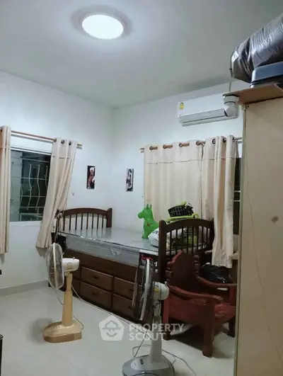 Cozy bedroom with air conditioning and natural light, featuring a single bed and modern decor.