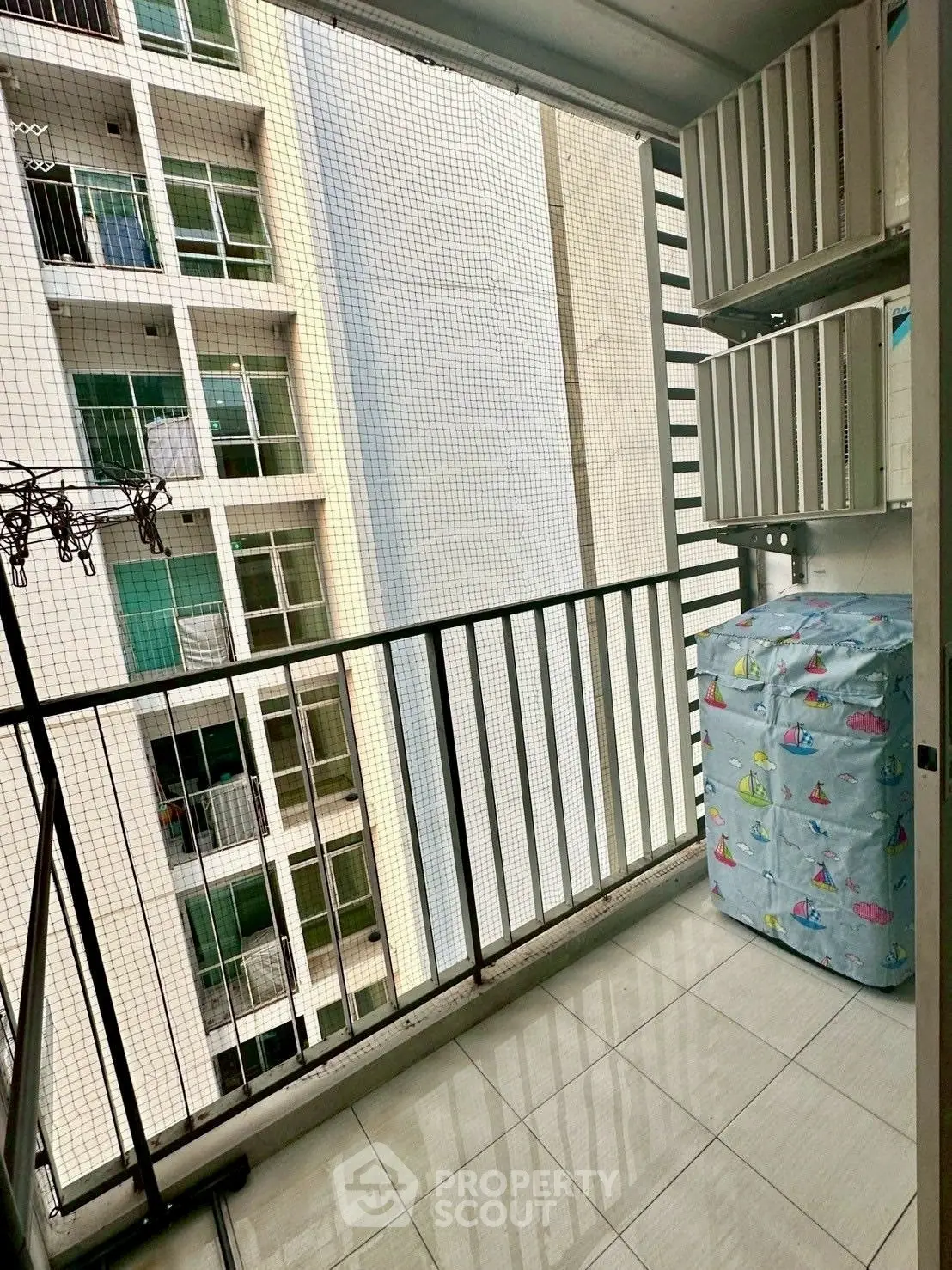 Spacious balcony with safety netting and tiled flooring in modern apartment building.