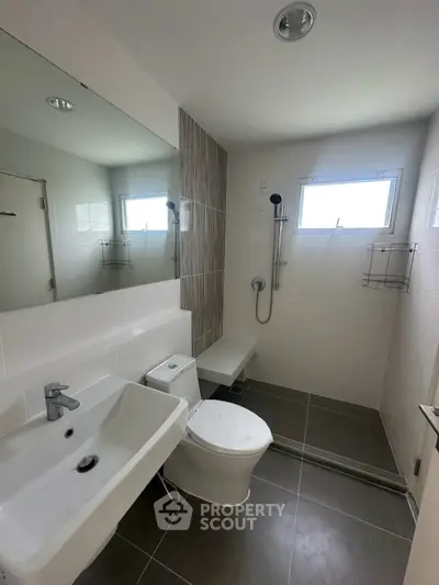Modern bathroom with sleek fixtures and natural light, featuring a spacious shower area and contemporary design.