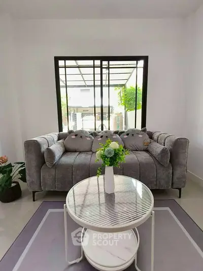 Chic living room with plush gray sofa and garden view, perfect for relaxation.