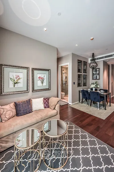 Elegant living room with stylish decor and dining area, featuring plush sofa and chic glass tables.