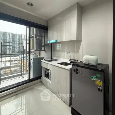 Modern kitchen with balcony view, featuring sleek cabinetry and compact appliances.