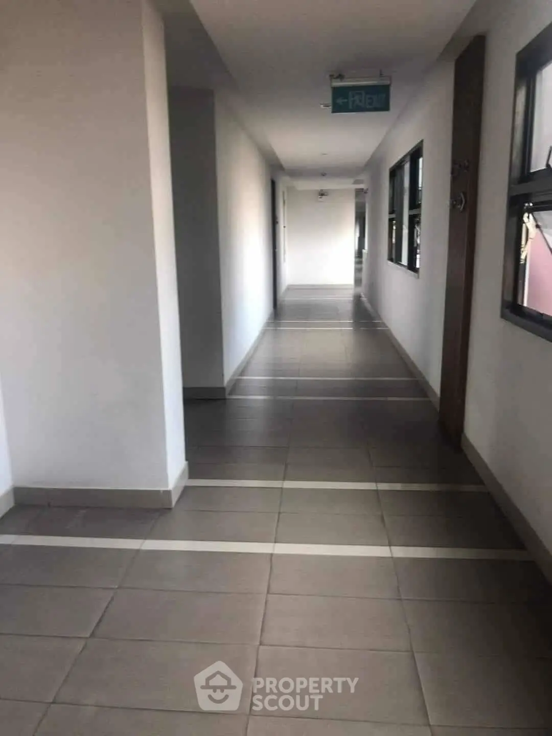 Modern apartment hallway with tiled flooring and exit sign.
