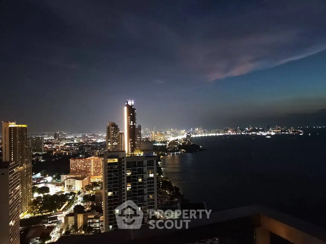 Stunning cityscape view from a high-rise balcony overlooking the ocean at dusk.