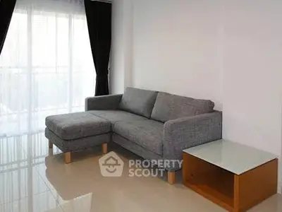 Modern living room with sleek gray sofa and natural light from large window.