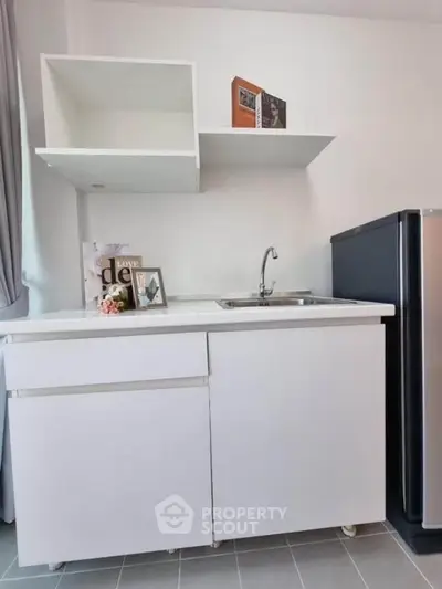 Compact kitchen with sleek white cabinets and modern appliances in a stylish apartment.