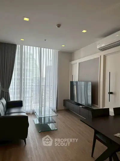 Modern living room with sleek furniture and large windows offering city views.