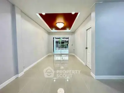 Spacious modern interior with glossy tiles and elegant ceiling light, perfect for versatile living space.