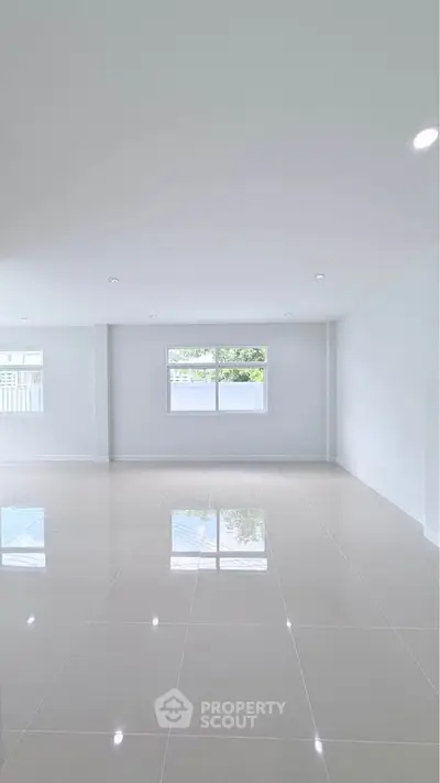 Spacious empty room with glossy tiled floor and large window, perfect for customization.